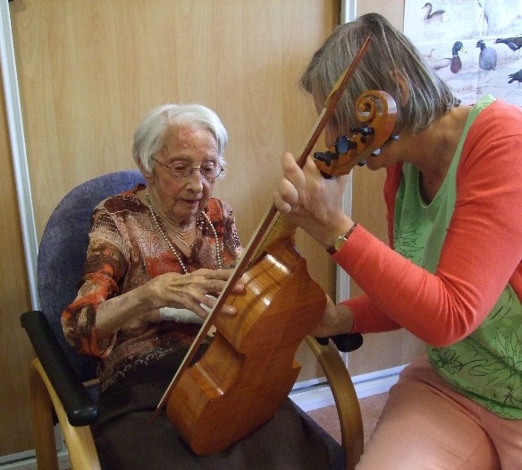 foto, mevrouw Kruuk van 95 tokkelt lichte en donkere tonen op de kleine viola da gamba